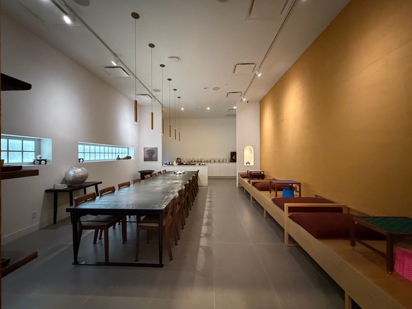 TEO Nomad, New York — one long table with low bench seating along an ochre wall